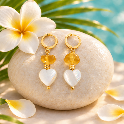 Aretes de ámbar dominicano y corazón de madreperla sobre piedra clara con flor tropical