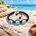 Pulsera de macramé de larimar y piedra de lava sobre madera clara en la playa, con cuerda y cuero