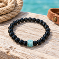 Pulsera de ónix y larimar sobre madera clara con cuerda y cuero