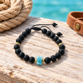 Pulsera de ónix mate, larimar y detalles de baño de oro sobre madera clara con cuerda y cuero
