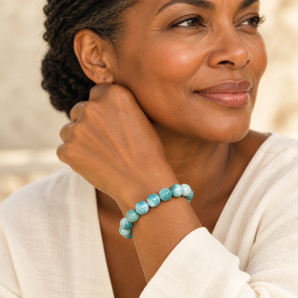 Pulsera de bola de Larimar lucida por Maria, vista cercana de la muñeca con manga marfil