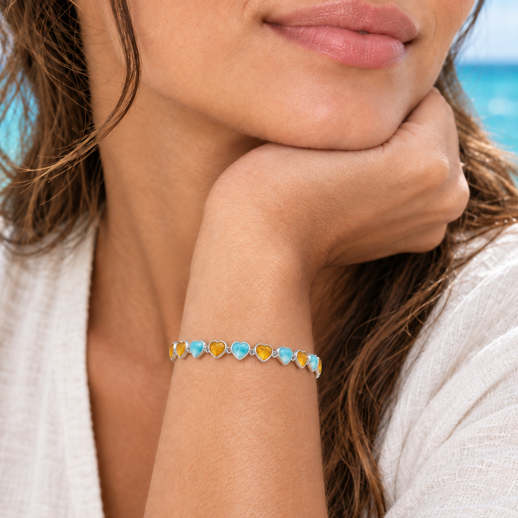 Pulsera de corazones con Larimar y Ámbar cerrada en la muñeca de una modelo con la mano bajo el mentón