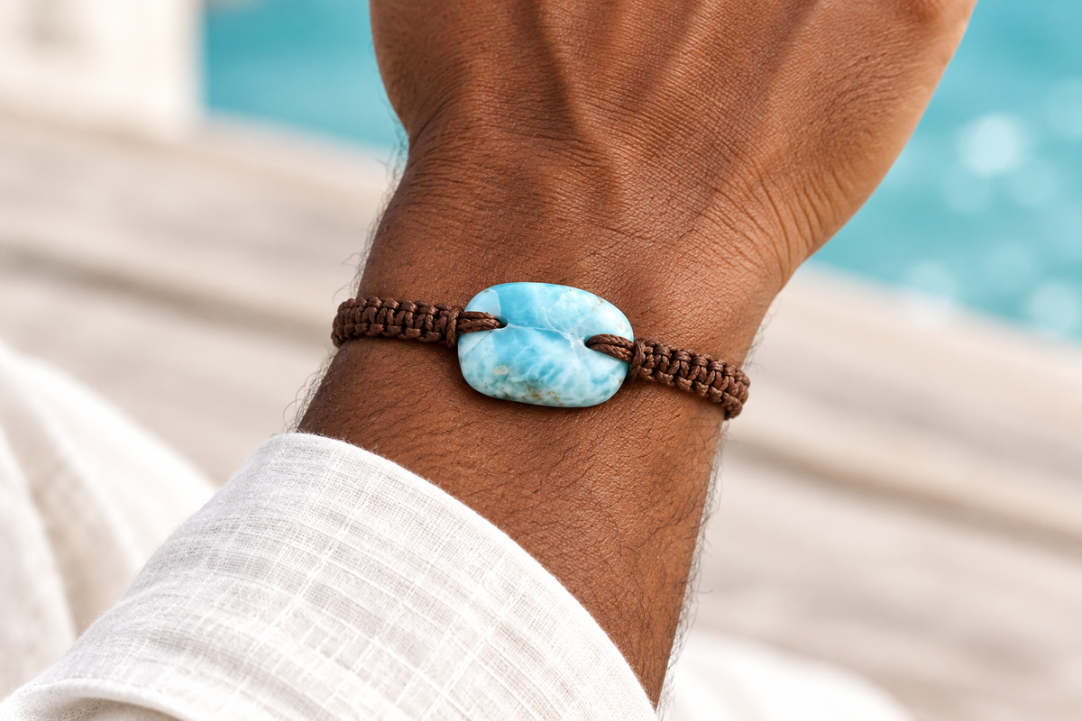 Pulsera de larimar y macramé marrón puesta en la muñeca de un hombre, con las uniones laterales de la piedra alineadas con el tejido
