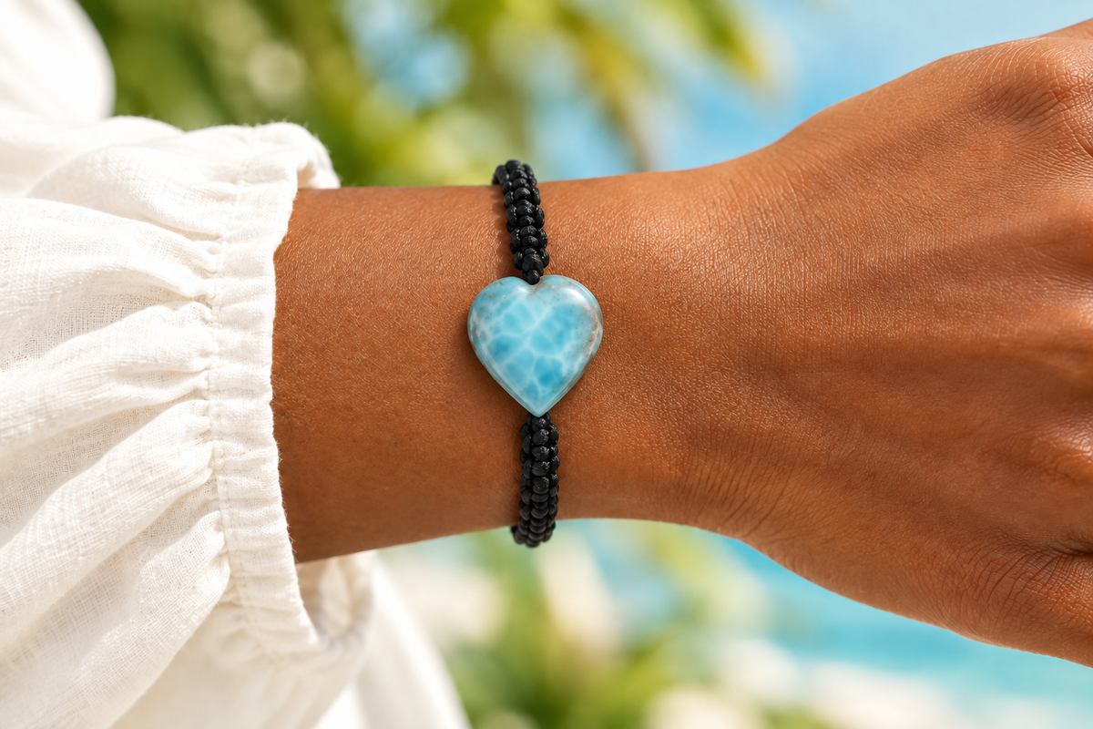 Pulsera de macramé negro con corazón de larimar azul puesta en la muñeca, punta del corazón hacia la trenza inferior